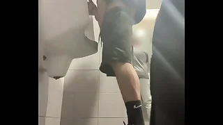 2 boys in sneakers having fun at public toilets' urinal